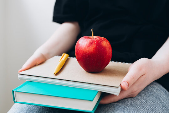Teen girl with books and apple, educational setting