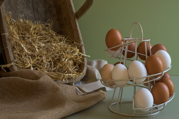 Farm chicken eggs stacked into a wire tower. Basket filled with straw and free range hens eggs.
