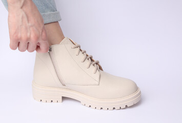 Woman unfastens the zipper of her white leather boots