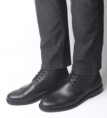 Male legs in black leather brogue boots on a white background