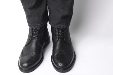 Male legs in black leather brogue boots on a white background
