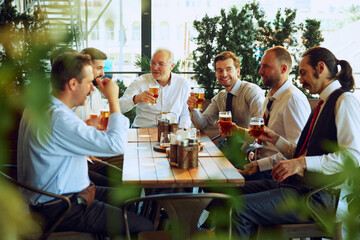 Group of men, business people, colleagues meeting at outdoor bar and drinking beer, discussing successful projects and partnership. Concept of business, meeting, fun, celebration, Oktoberfest
