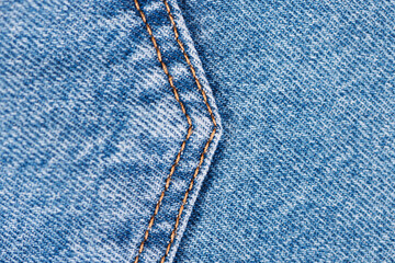 The double seam of the blue jeans is curved at the back pocket, close-up. Small depth of field. Selective focus.