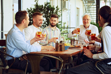 Group of men, business people, colleagues meeting at outdoor bar and drinking beer, discussing successful projects and partnership. Concept of business, meeting, fun, celebration, Oktoberfest