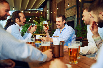 Business people, men enjoying relaxed meeting at the bar, with beers in hand, discussing business plans and celebrating growth. Concept of business, meeting, celebration, leisure time, Oktoberfest