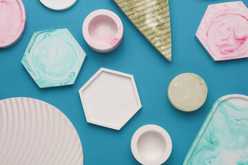 Plaster geometric shapes, decorative trays on blue background. Top view