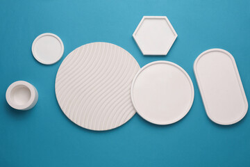 Plaster geometric shapes, decorative trays on blue background. Top view