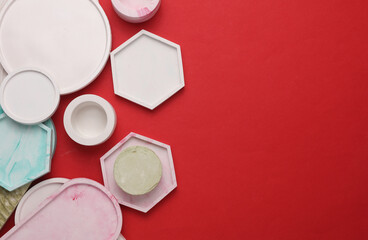 Plaster geometric shapes, trays on red background. Top view
