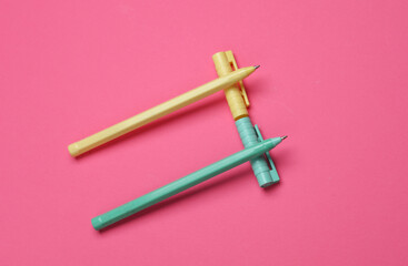 Colored pens on a pink background