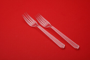 Transparent plastic forks on a red background