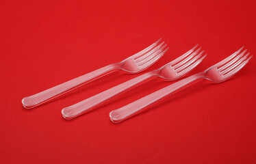 Transparent plastic forks on a red background