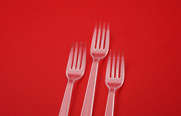 Transparent plastic forks on a red background