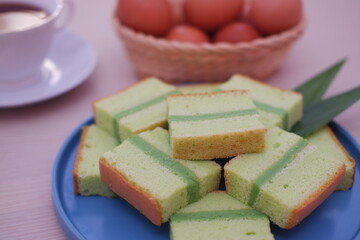 pandan cake on a blue plate with cup of tea