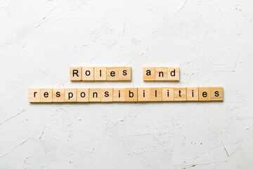 roles and responsibilities word written on wood block. roles and responsibilities text on table,...