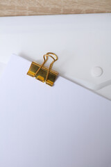 Golden binder with white empty sheet of paper on the table