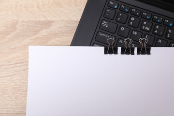 White blank sheet of paper with Black binders and laptop on the table