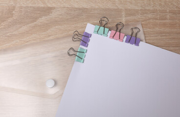 White blank sheet of paper with colored binders on table