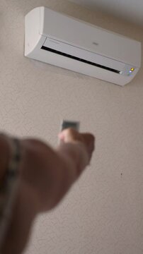 woman turns on air conditioner with remote