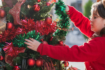 Young girl decorating a Christmas tree outdoors