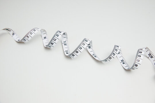 Curled measuring tape on clean white background