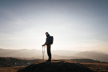 Obraz premium Solo hiker on mountain at sunrise with trekking poles