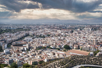 A panoramic view of Alicante, one of Spain's largest cities, showcasing its expansive urban landscape beneath a partly cloudy sky, offering a picturesque and vibrant scene.