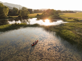 Happy couple enjoying a summer canoe ride on the lake, relaxing surrounded by beautiful green...