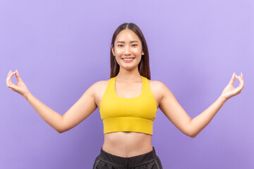 Smiling  asian woman in yellow sportswear performing a fitness stretch, set against a bold purple background.