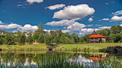 View of the pond, blooming meadow, forest and cottages in village at summer timelapse hyperlapse