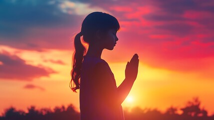 Teenage girl in prayer pose. Against the backdrop of the sunrise sunset sky