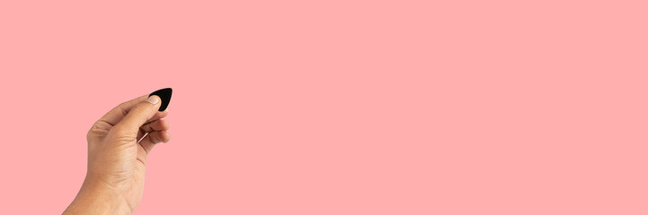 Obraz premium Black male hand holding a guitar pick isolated on pink background banner