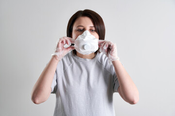 Young woman with surgical mask for protection from corona virus over grey background with copy space