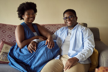 Smiling young African couple relaxing together on a sofa at home