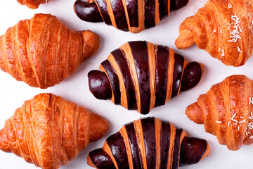 Croissants with chocolate made of two-colored dough on the white table. Puff pastry dessert. Top view