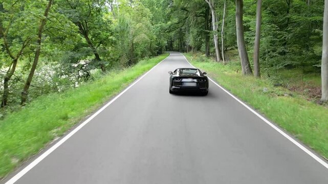 supercar driving on road in the forest backwards tail aerial luxury high end rich millionaire