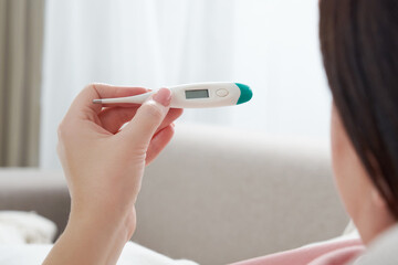 Woman holding a digital thermometer. Concept of fever, flue, virus and quarantine 