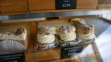 A display case features fresh cream scones and cheesecake slices, showcasing a tempting selection of desserts with visible price tags.