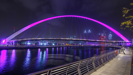 Obraz premium Pedestrian Bridge over the Dubai Water Canal night timelapse, United Arab Emirates