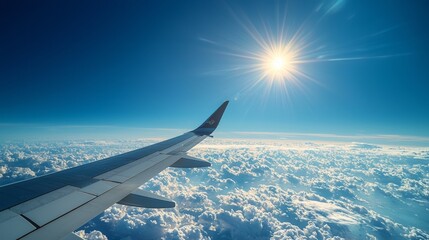 Fototapeta premium View of an airplane wing above the clouds with the sun shining