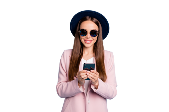 Portrait of cheerful positive girl in eyeglasses eyewear using  her mobile phone device following commenting posts wearing pink topcoat isolated over blue background