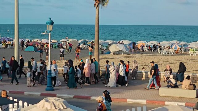 Tetouan, Morocco - 20 August 2024 - people walking and sitting in the beach of Martil in north of Morocco during summer
