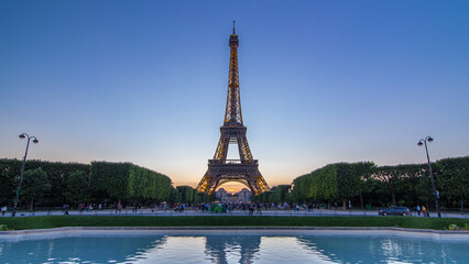 Obraz premium Eiffel Tower day to night timelapse and people sitting on the grass in the evening in Paris, France