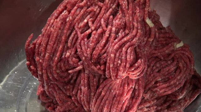 minced meat comes out of the mincing machine into the cooking bowl