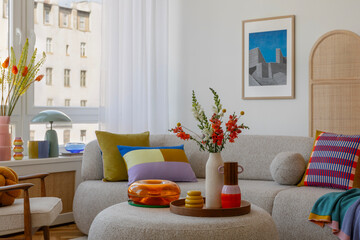 Bright and airy living space featuring a stylish sofa, vibrant cushions, and a round ottoman with a...