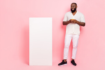 Photo of funky dreamy young man wear white shirt reading modern device empty space isolated pink...