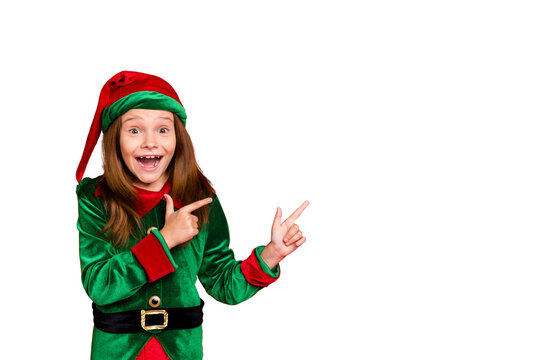 Portrait of impressed funky elf in hat cap showing ads with her index fingers screaming wow omg see magic wearing green costume isolated over red background