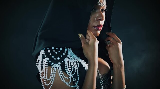 fantasy gothic african american woman vampire posing in night studio. Mystical beauty gorgeous face, creative design halloween costume evil dark queen Black dress hood cape on head. Sexy girl wizard