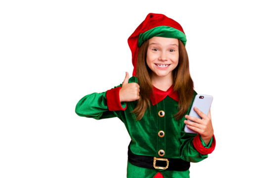Portrait of cheerful schoolkid with long red head haircut showing thumb up holding gadget wearing green hat headwear cap costume isolated over red background