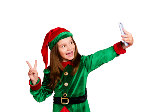 Portrait of lovely elf in hat with red head making selfie v-signs wearing green fairy costume hat cap isolated over red background
