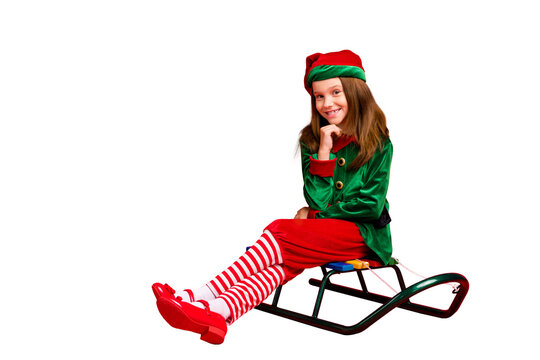 Portrait of her she nice attractive charming cheerful cheery funny sweet pre-teen elf santa claus apparel look outfit sitting on sled isolated over bright vivid shine red background